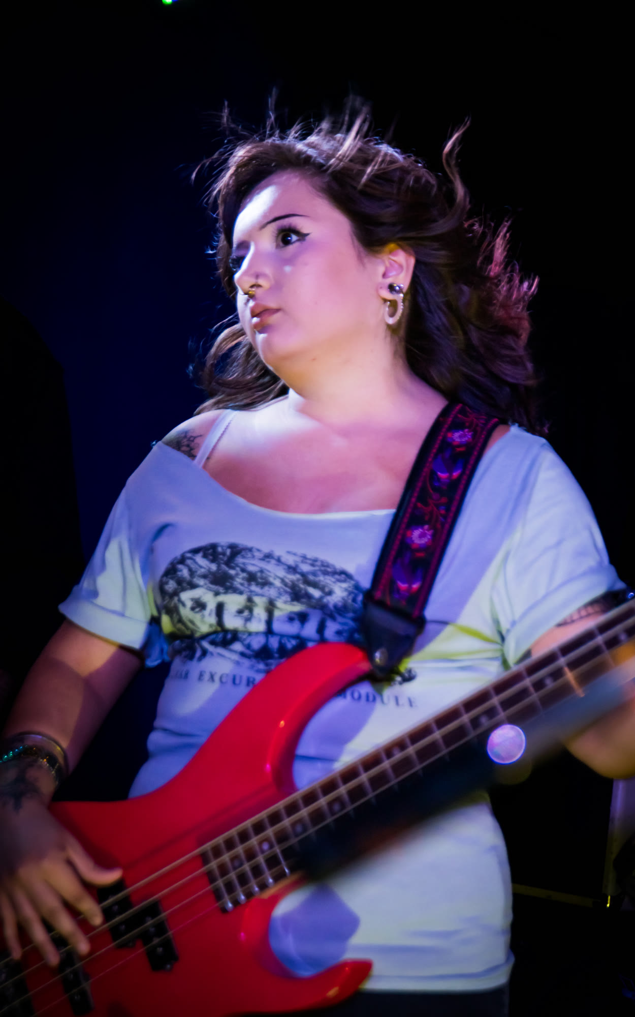 Bassist in a light shirt plays a red bass