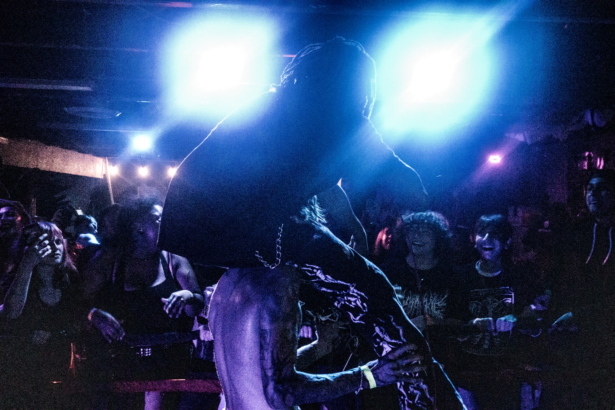 Performer leans over the crowd under blue stage lights