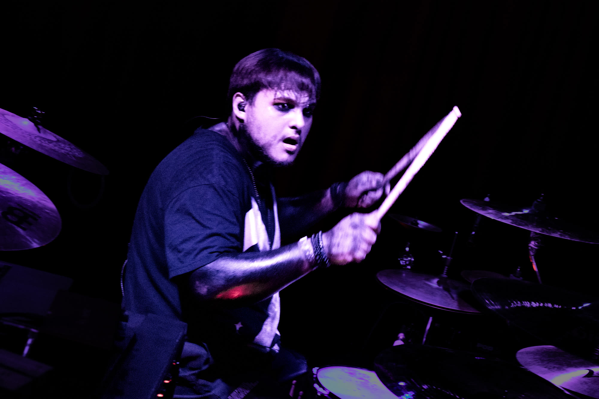 Drummer plays under purple light